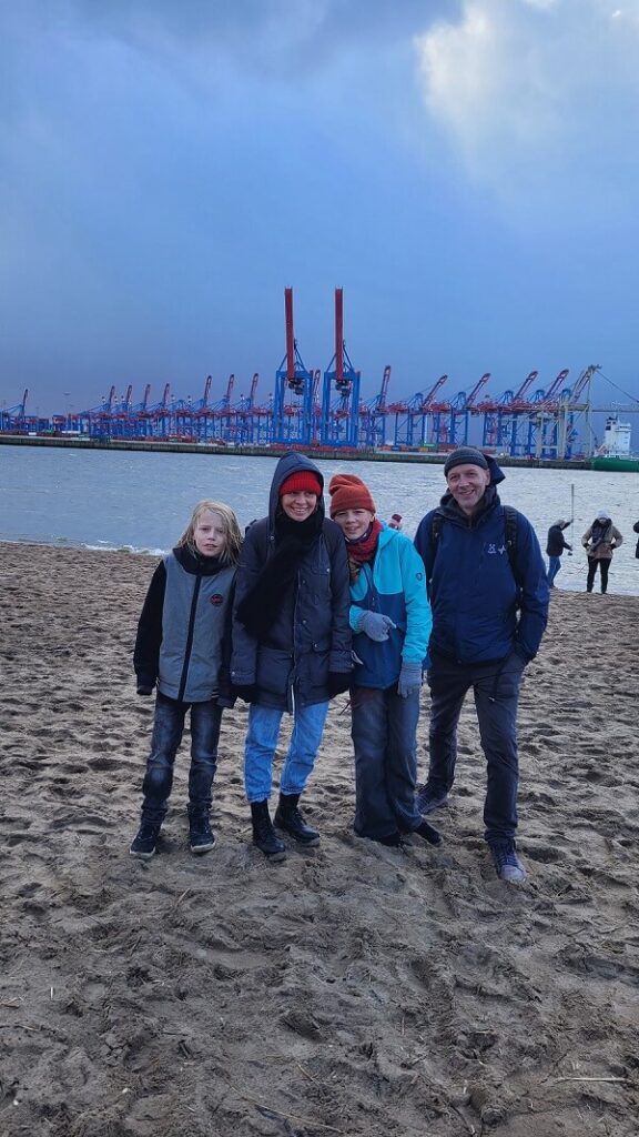 Familie am Elbstrand Hamburg, im Hintergrund Hafenkräne